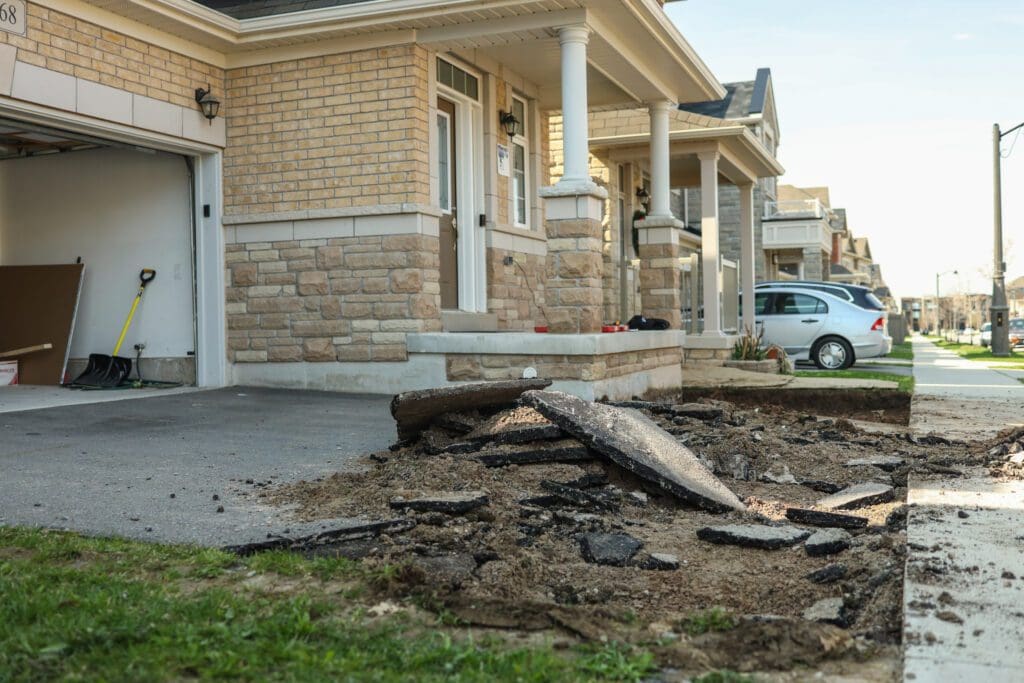 Asphalt driveway with broken chunks of asphalt revealing gravel underneath