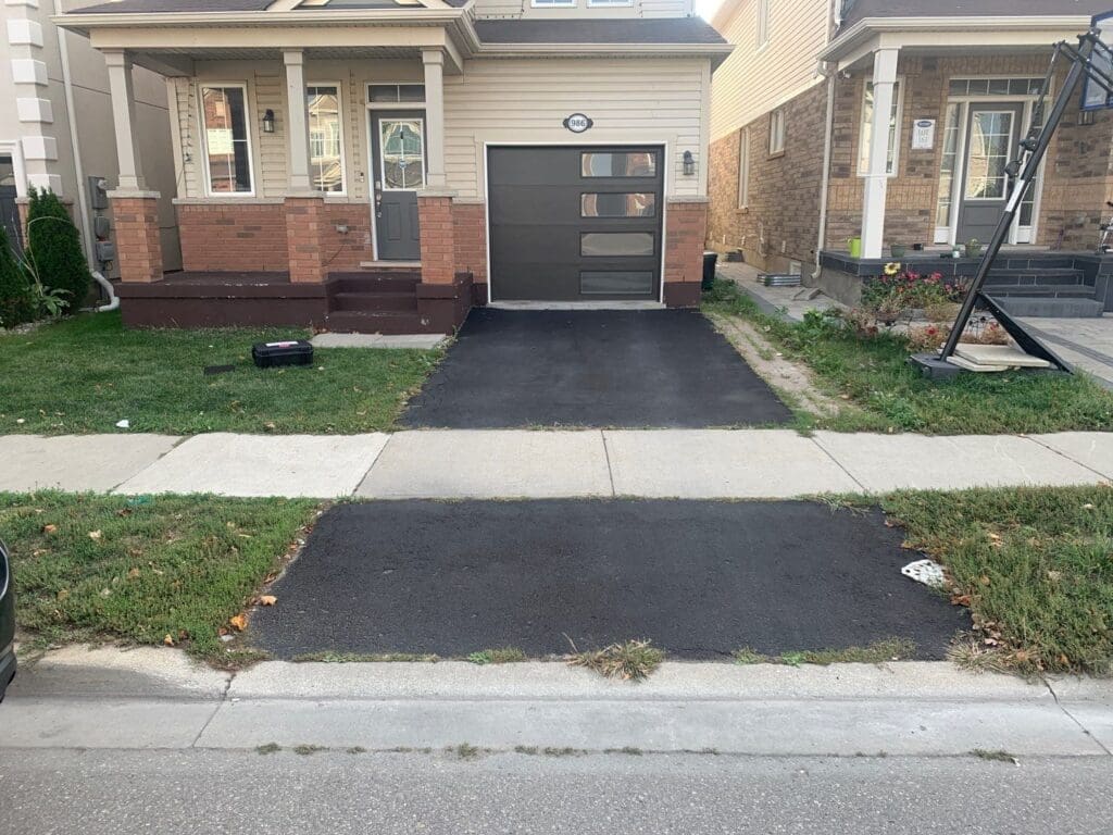 Asphalt driveway with a sidewalk through the middle.