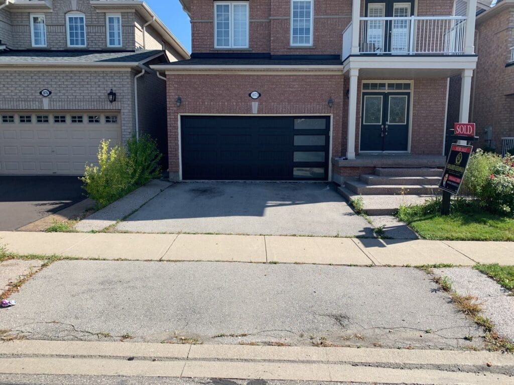 Asphalt driveway with some cracks that have weeds growing within them