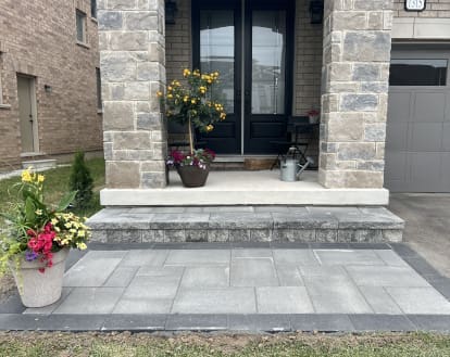 Intricate paver stone design consisting of different shades of grey pavers of varying sizes on a small platform in front of a porch and single step in front of the porch, exemplifying Interlocking paver work on a small front entrance