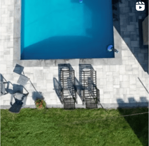 Instagram video post thumbnail showing aerial view of large grey paver stone patio around large in-ground pool.