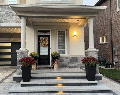 Low front porch with 3 wide and long steps, each lit up with a small warm yellow recessed light fixture, exemplifying Landscape Lighting work in a small area