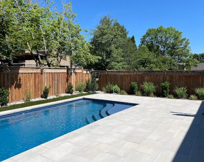 Patio surrounding a pool consisting of large light grey rectangular paver stones in a linear pattern exemplifying Interlocking Patio Stone work in a small area