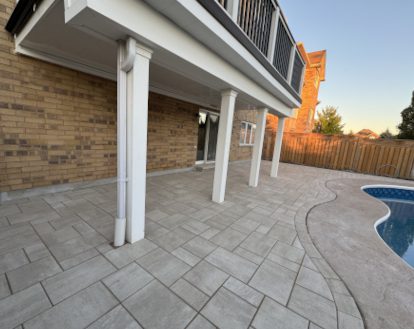 Patio surrounding a pool consisting of grey rectangular paver stones of varying sizes in an intricate pattern exemplifying Interlocking Patio Stone work in a small area