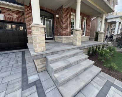A 5 step front porch with a wider platform spanning half the width of the house, exemplifying paver stone work on a large porch