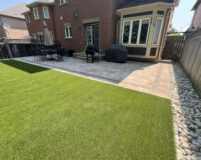 Large green artificial turf area in the middle of a residential backyard, exemplifying artificial turf work on a medium-sized area
