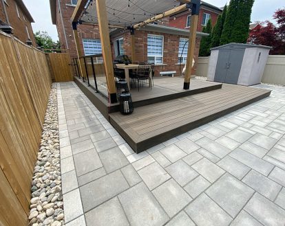 Paver stone walkway consisting of grey rectangular pavers of varying sizes going around a large wooden gazebo and transitioning into a smaller patio area, exemplifying Interlocking stone walkways on a larger walkway