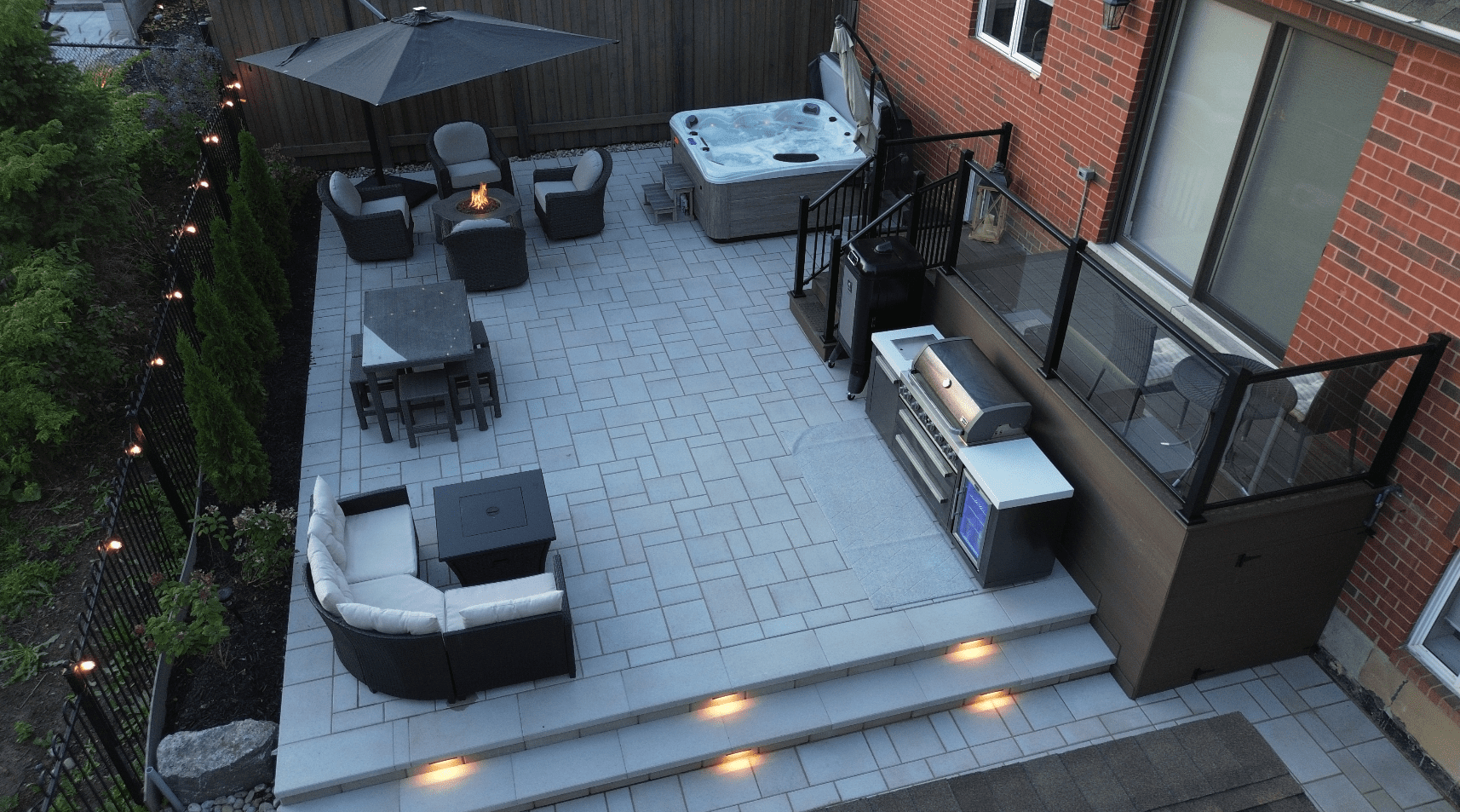 Aerial shot looking down on a patio with new grey interlocking patio stones of various sizes, including custom interlocking stone stairs finished with led lights integrated into each set of risers