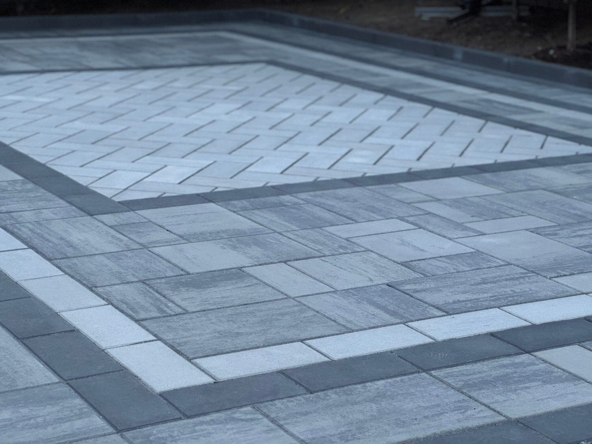 Elegant interlocking driveway and front walkway illuminated with built-in LED landscape lighting at dusk.