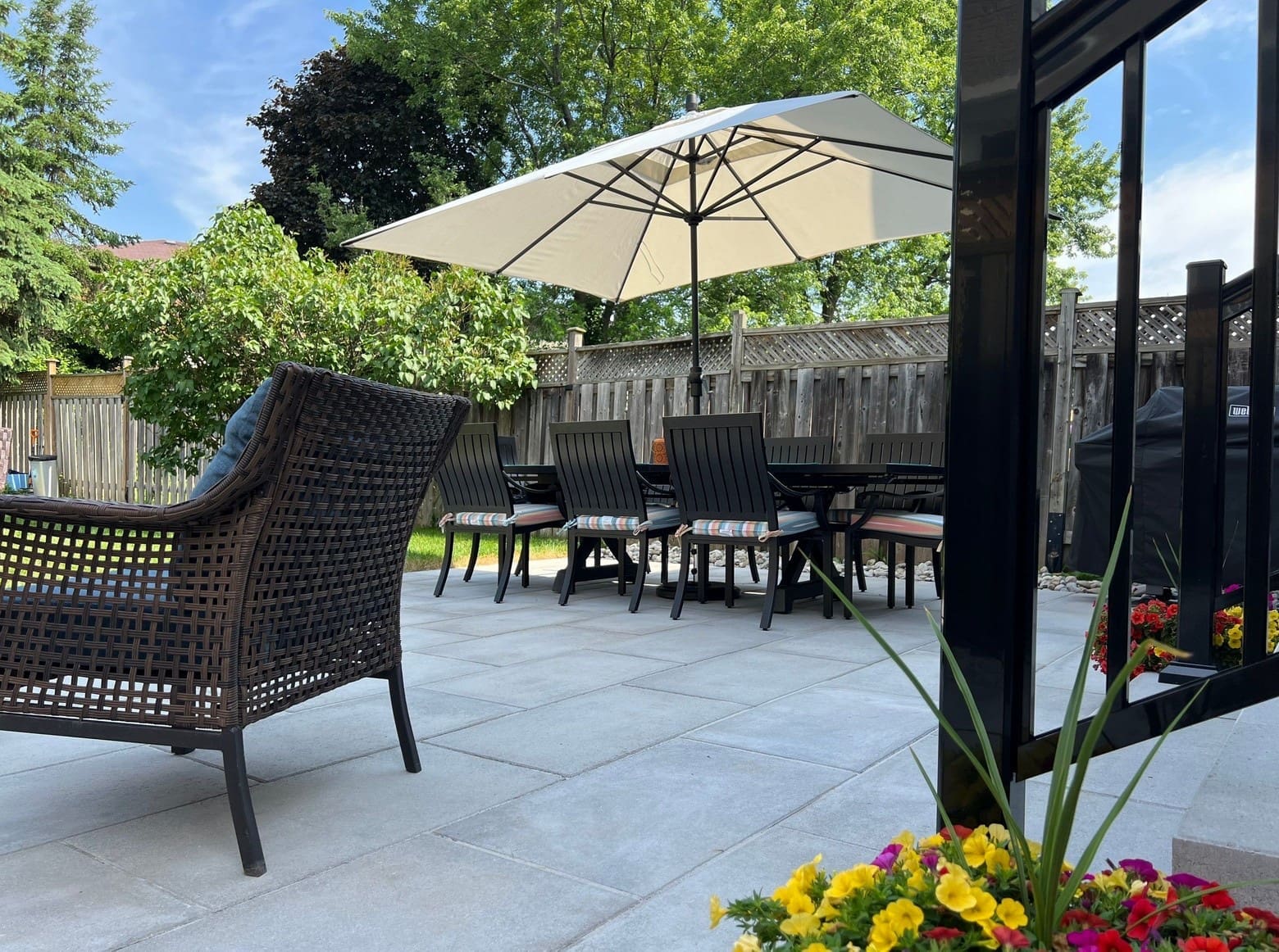 Modern outdoor seating area on an interlocking stone patio with potted plants, designed for summer relaxation.