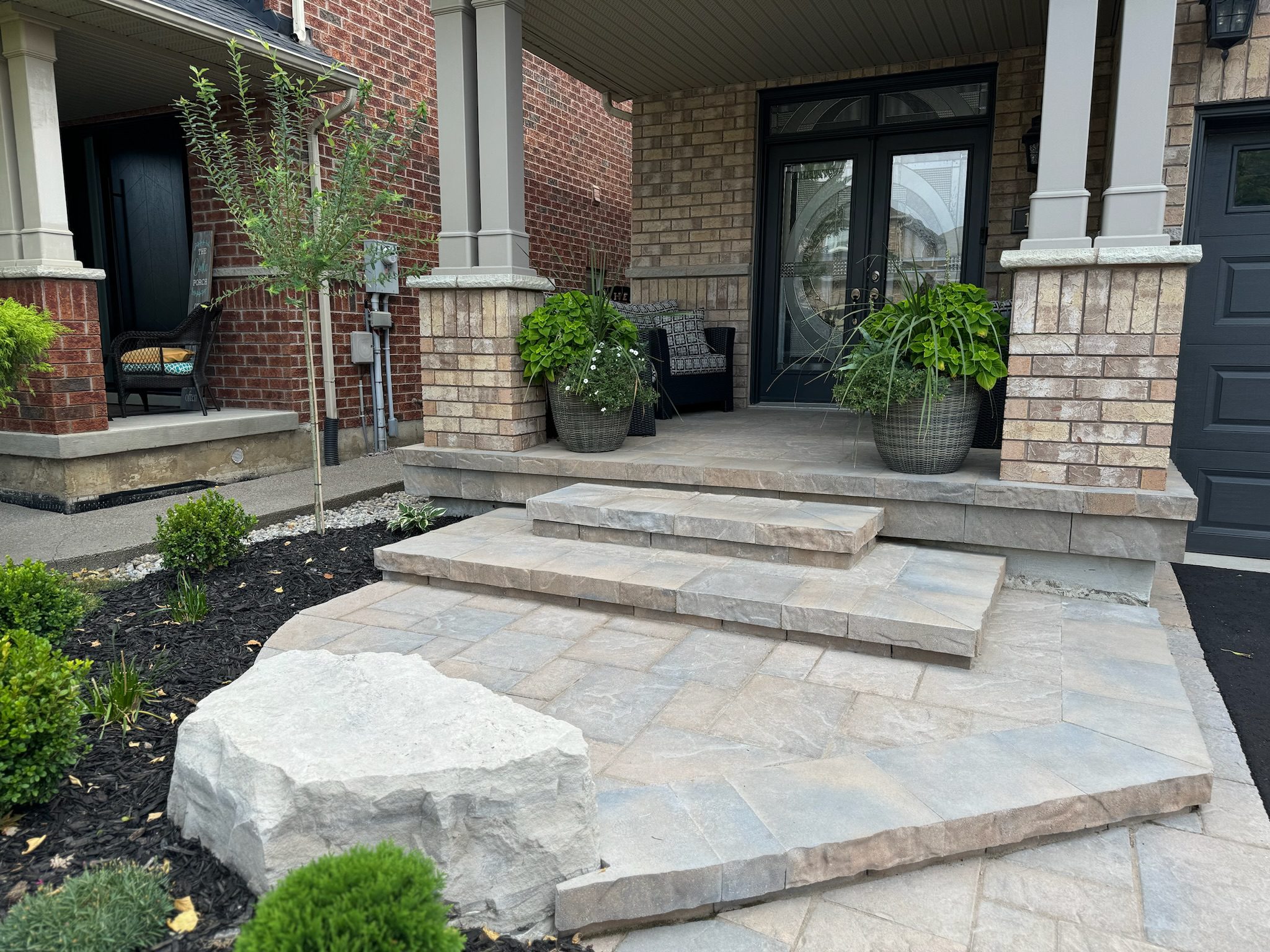 Elegant interlocking driveway and front walkway illuminated with built-in LED landscape lighting at dusk.