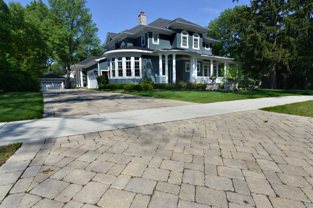 Elegant home with a spacious interlocking stone driveway and manicured front lawn, showcasing curb appeal and functional design.