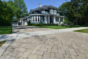 Elegant home with a spacious interlocking stone driveway and manicured front lawn, showcasing curb appeal and functional design.