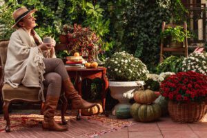 Cozy fall landscaping ideas with seasonal flowers, pumpkins and outdoor seating.