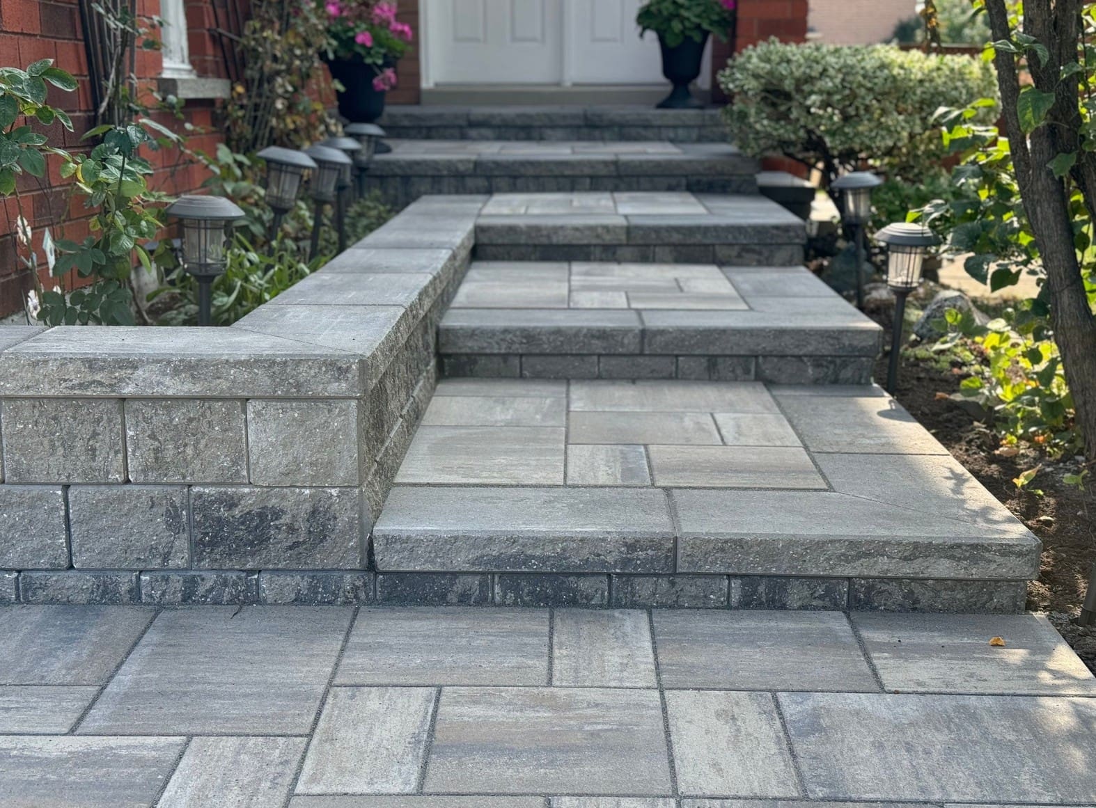 Interlocking paver walkway and front steps with wide landing leading to a home entrance.