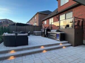 Modern interlocking patio design with steps, built-in lighting and outdoor kitchen.