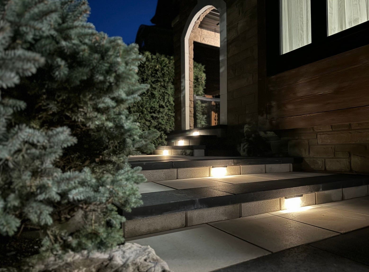 Interlocking paver walkway and front steps with wide landing leading to a home entrance.