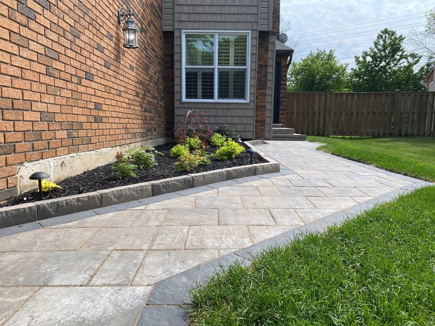 Interlocking paver walkway and front steps with wide landing leading to a home entrance.