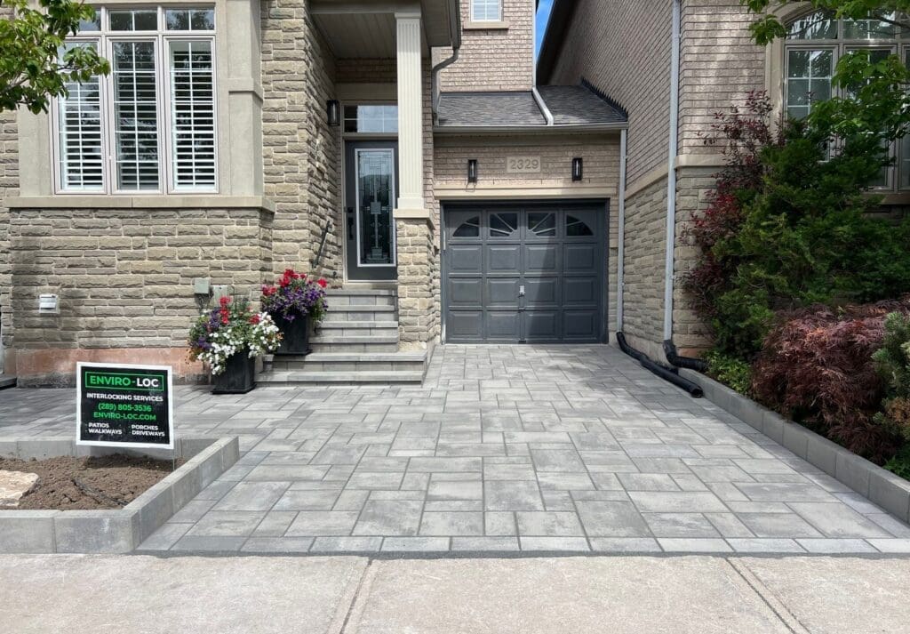 Professional landscaping in Hamilton featuring interlocking stone driveway and garden beds.